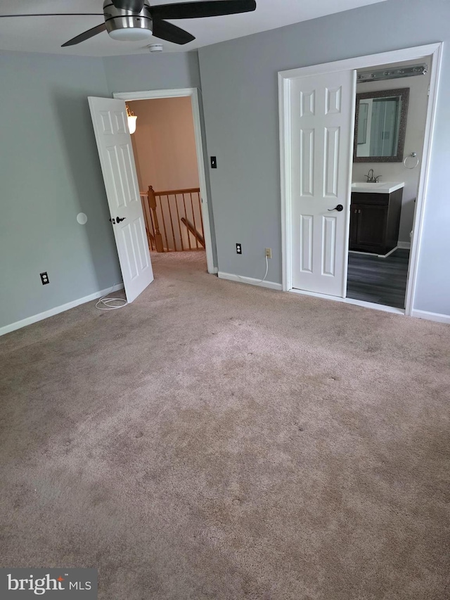 unfurnished bedroom featuring ensuite bath, carpet flooring, baseboards, and a sink