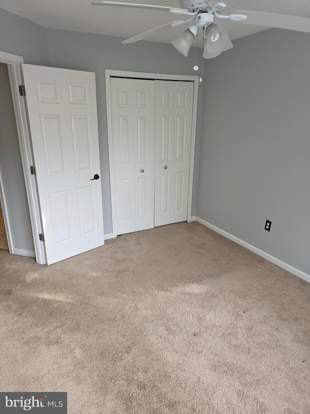 unfurnished bedroom with carpet, a closet, a ceiling fan, and baseboards