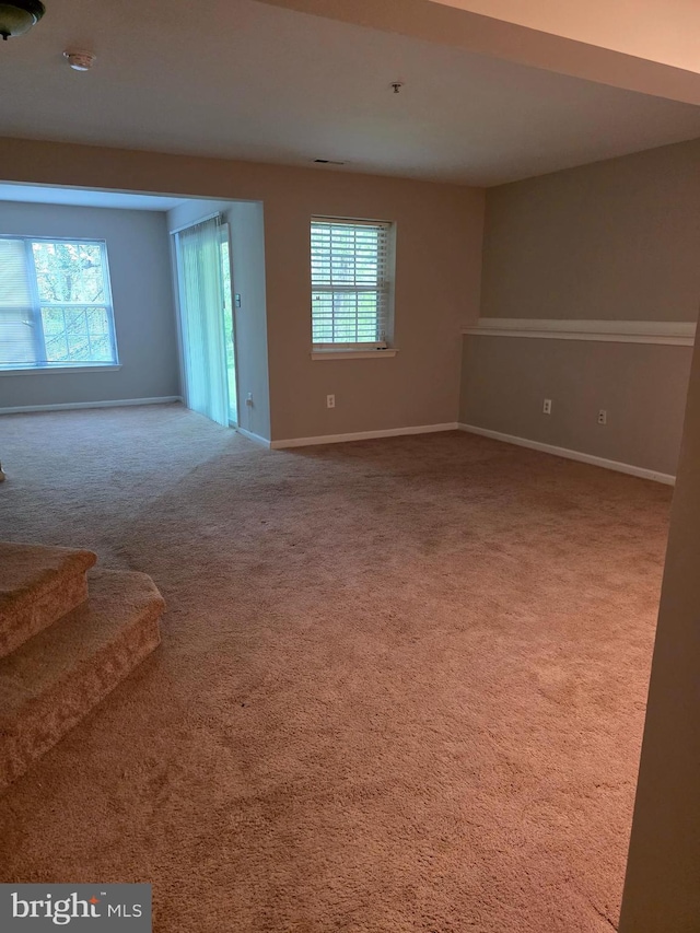 unfurnished living room featuring stairs, carpet flooring, and baseboards