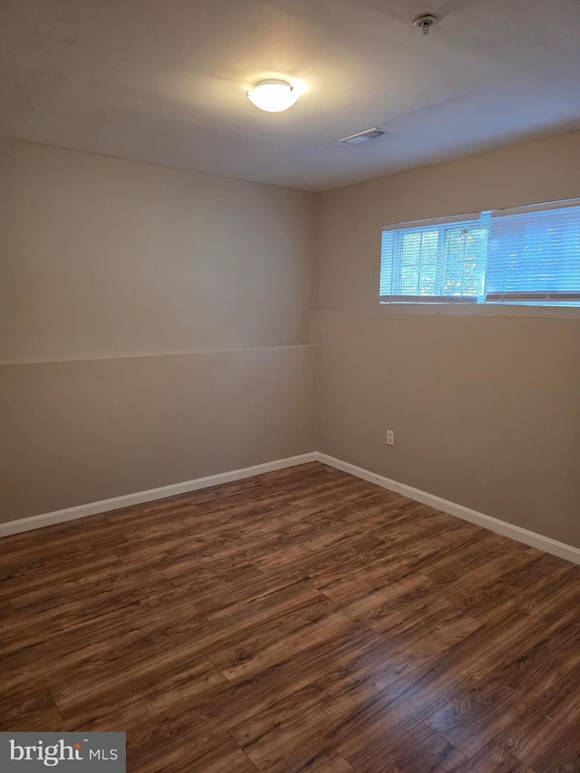 spare room featuring baseboards and dark wood-style floors