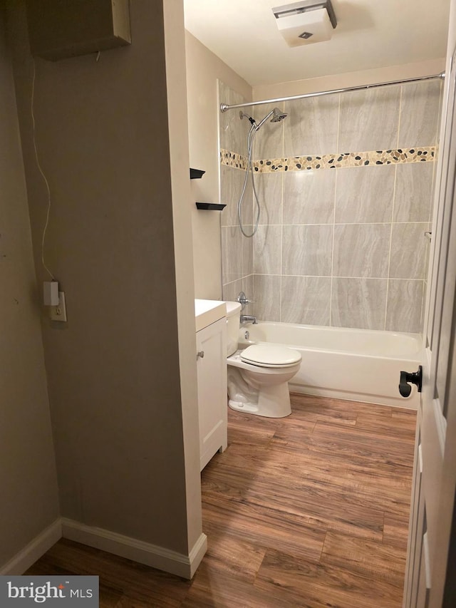 bathroom featuring toilet, baseboards, wood finished floors, vanity, and shower / tub combination