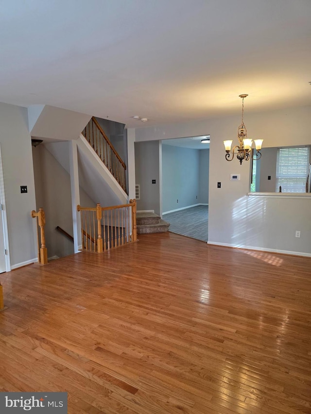 interior space with a chandelier, wood finished floors, visible vents, and baseboards