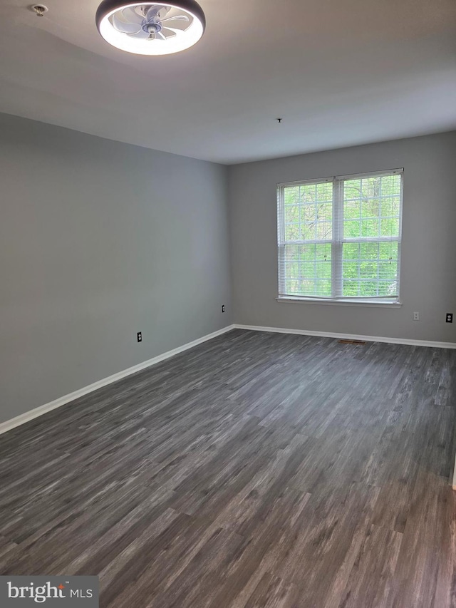unfurnished room with baseboards and dark wood-style flooring