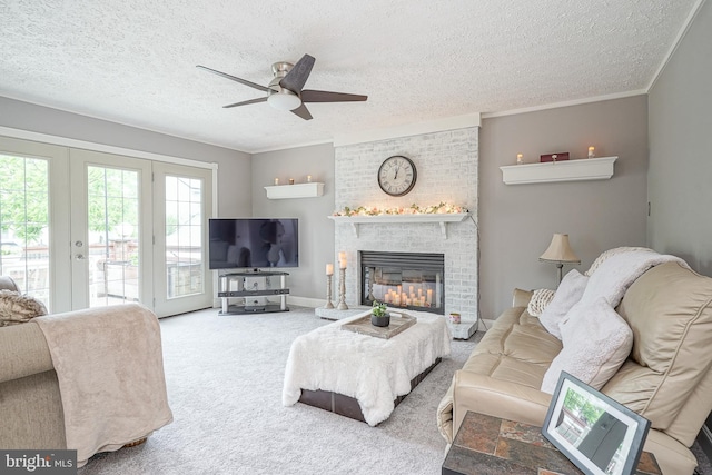619 Walden Way, Lumberton, NJ 08048 - carpeted living area with french doors, a ceiling fan, a textured ceiling, a brick fireplace, and crown molding