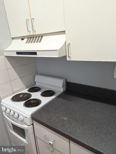 kitchen featuring backsplash, dark countertops, white cabinets, extractor fan, and electric stove