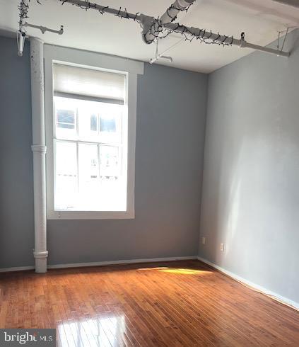 unfurnished room with baseboards and wood finished floors