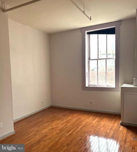 unfurnished room with baseboards and wood finished floors