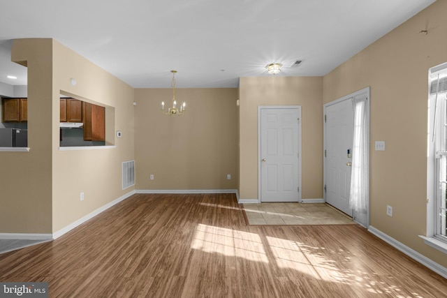 foyer entrance featuring light wood-style floors, visible vents, baseboards, and a chandelier