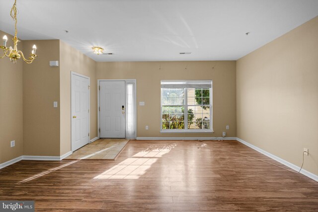 entrance foyer featuring baseboards, a chandelier, and wood finished floors