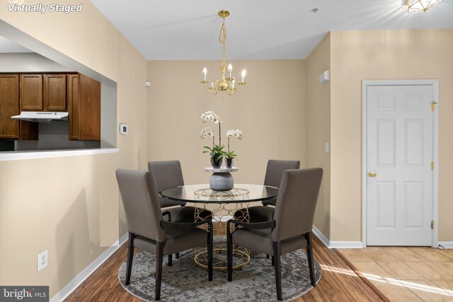 dining space with baseboards, an inviting chandelier, and wood finished floors