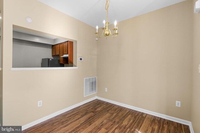 unfurnished dining area with a notable chandelier, visible vents, baseboards, and dark wood-style floors