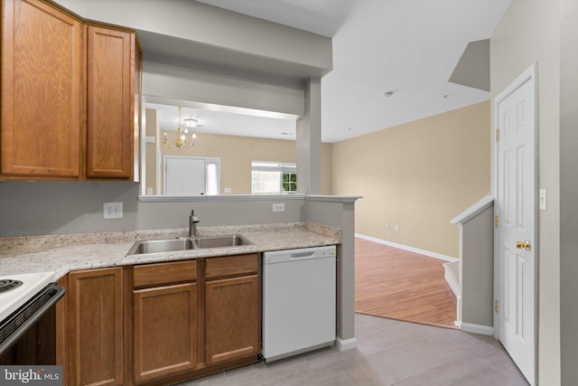 kitchen with a chandelier, a sink, white appliances, and brown cabinetry