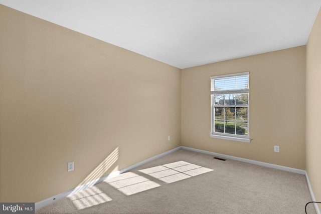 carpeted spare room featuring baseboards and visible vents