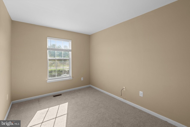 carpeted empty room featuring baseboards and visible vents
