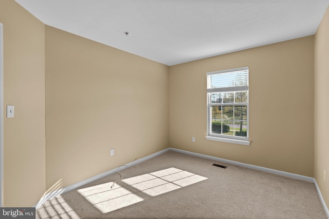 carpeted empty room featuring baseboards and visible vents