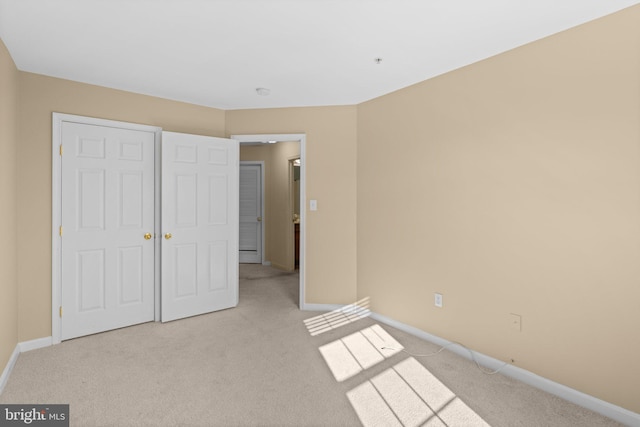 unfurnished bedroom featuring light carpet and baseboards