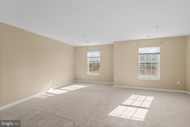 carpeted spare room featuring visible vents and baseboards