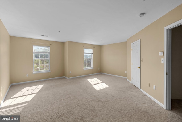 carpeted empty room featuring visible vents, baseboards, and a healthy amount of sunlight