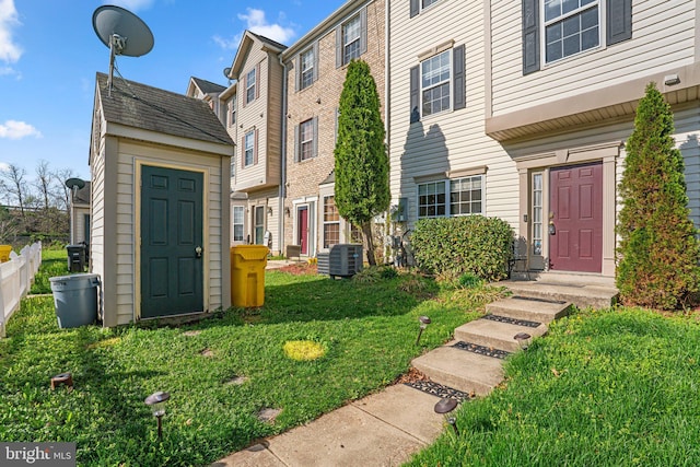 entrance to property featuring a yard, central AC unit, and fence