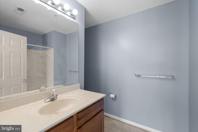 bathroom featuring a shower, vanity, baseboards, and visible vents