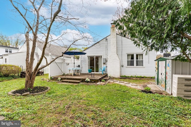 rear view of house with an outbuilding, a storage unit, a deck, and a yard