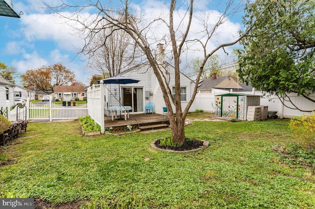 view of yard featuring a fenced backyard, an outdoor structure, a wooden deck, and a shed