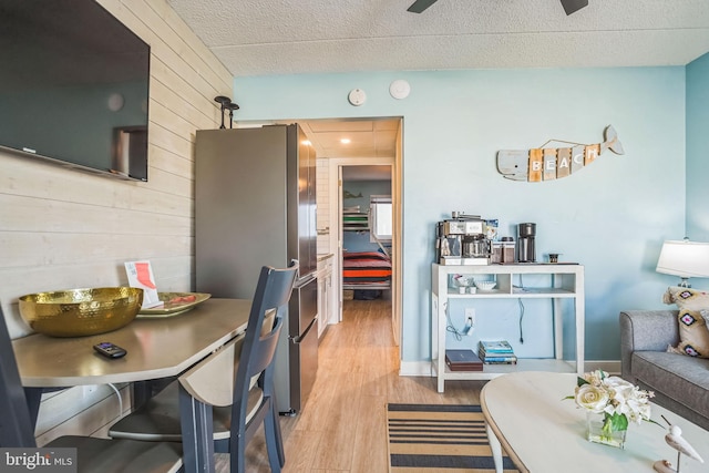 dining space featuring light wood-style flooring, a textured ceiling, and wood walls