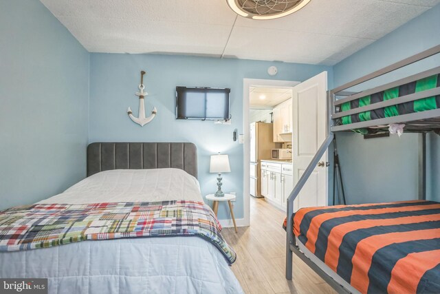bedroom featuring freestanding refrigerator and light wood-style floors