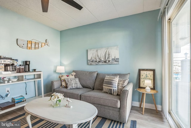 living room with baseboards, a ceiling fan, and wood finished floors