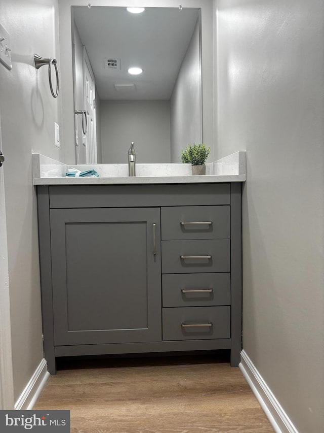 bathroom with baseboards, vanity, wood finished floors, and visible vents