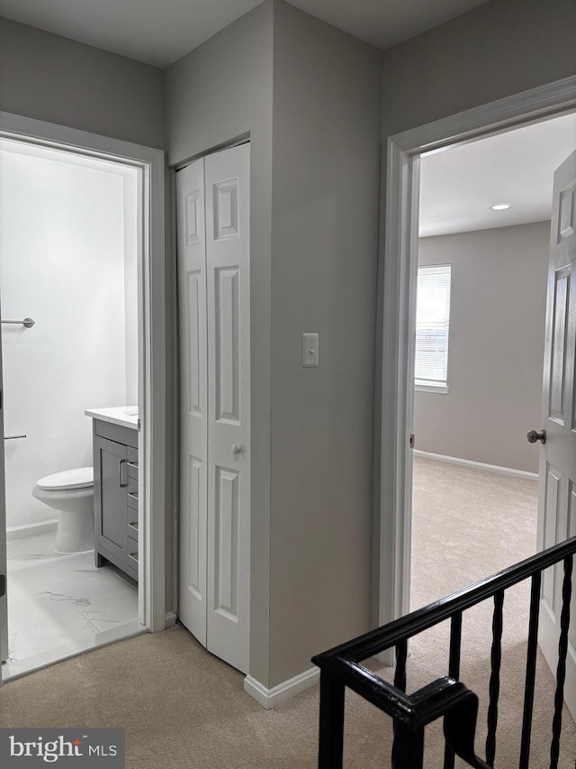 hall featuring baseboards and light colored carpet