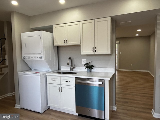kitchen with wood finished floors, a sink, stacked washing maching and dryer, light countertops, and dishwashing machine