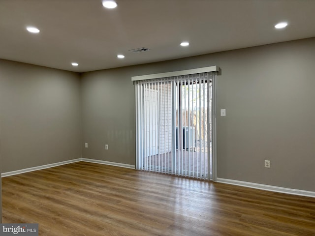 empty room featuring baseboards, wood finished floors, visible vents, and recessed lighting