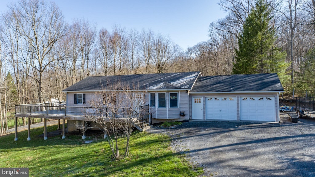 ranch-style home featuring a garage, a wooden deck, driveway, and a front yard