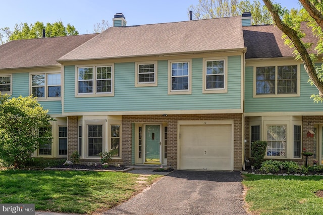 view of property featuring brick siding, driveway, a chimney, and a front yard