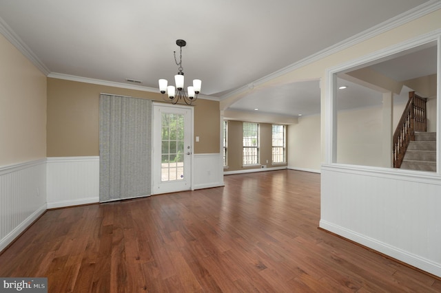 unfurnished dining area featuring a notable chandelier, wood finished floors, visible vents, and a wainscoted wall