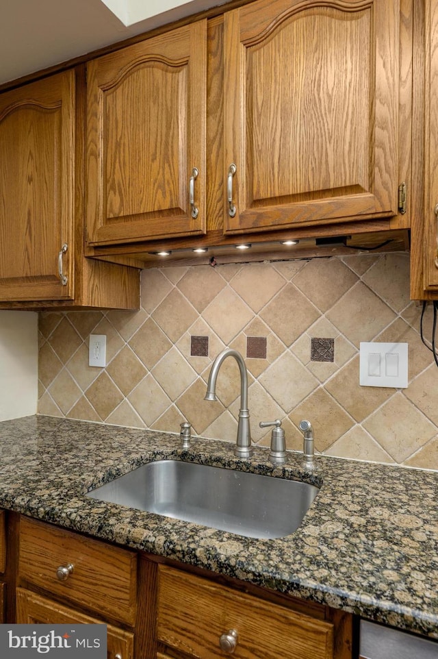kitchen featuring brown cabinetry, a sink, and tasteful backsplash