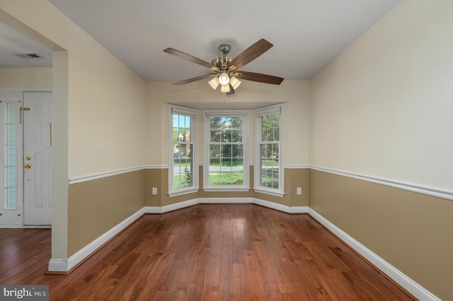 spare room featuring baseboards, ceiling fan, wood finished floors, and visible vents