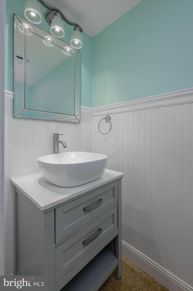 bathroom featuring vanity, speckled floor, and a wainscoted wall