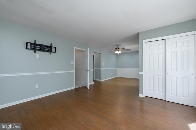 unfurnished living room featuring baseboards, a ceiling fan, and dark wood-style flooring