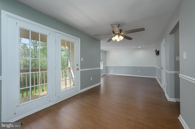 spare room with baseboards, a ceiling fan, and dark wood-style floors