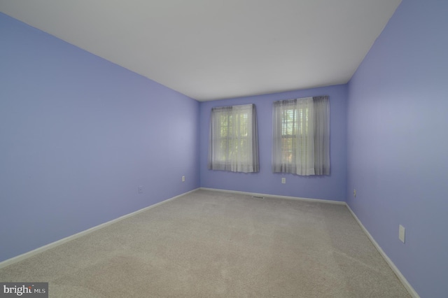 unfurnished room with baseboards and light carpet