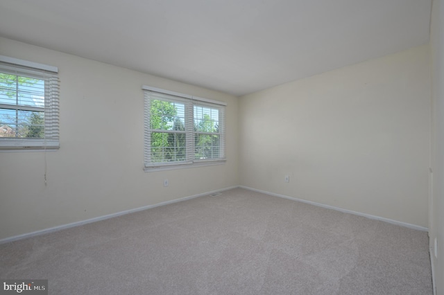 unfurnished room featuring carpet floors, baseboards, and a wealth of natural light