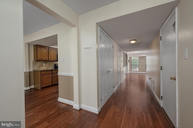corridor with baseboards and dark wood-type flooring
