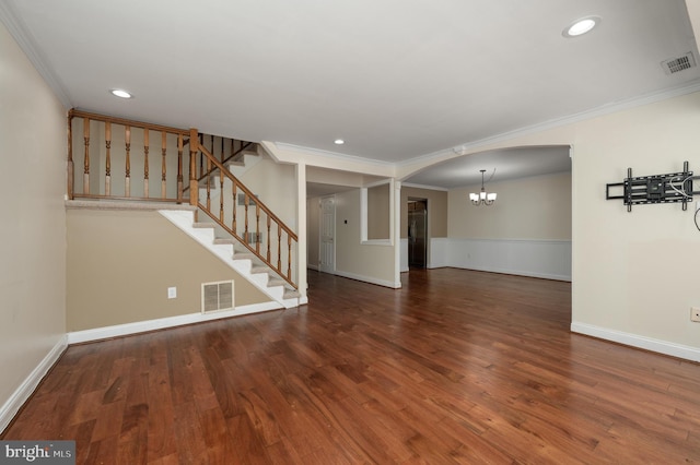 unfurnished living room with ornamental molding, a notable chandelier, wood finished floors, and visible vents