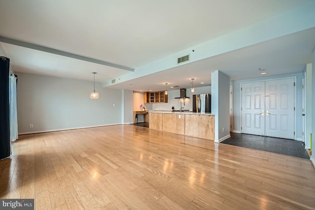 250 President St Unit 1001, Baltimore, MD 21202 - unfurnished living room with visible vents, light wood-type flooring, and baseboards