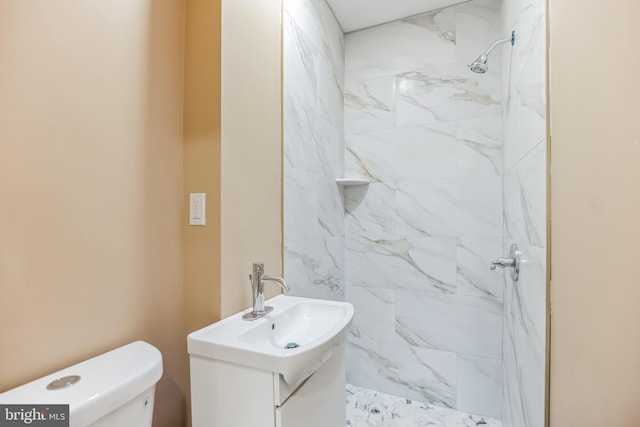 full bathroom with a tile shower, vanity, and toilet