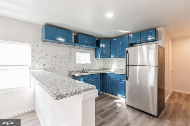 kitchen featuring blue cabinets, freestanding refrigerator, and light countertops