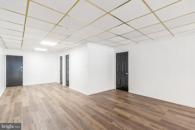 below grade area featuring baseboards, a paneled ceiling, and wood finished floors