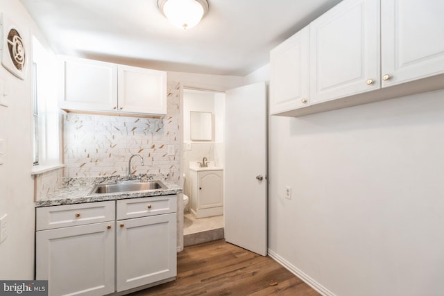 kitchen with wood finished floors, decorative backsplash, a sink, and white cabinets